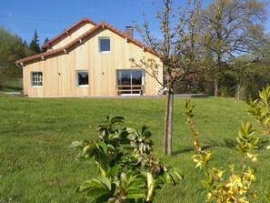 Ein zweistöckiges Holzhaus mit rotem Dach, einer Veranda und einem großen Fenster.