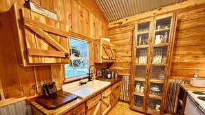 Une cuisine aménagée de style rustique, avec des meubles en bois, un évier, des placards et une cuisinière.