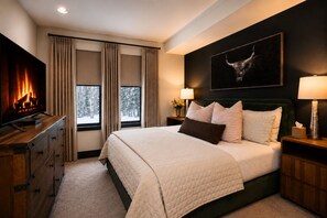 A hotel room with a bed, a television, a fireplace, and a painting on the wall. - Bear Creek Lodge 303c 1 Bedroom Hotel Room (Telluride)