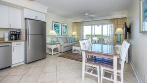 Una cocina moderna con refrigerador, cafetera y comedor con mesa y sillas.