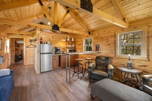 A wooden cabin interior with a kitchen, dining area, and seating.