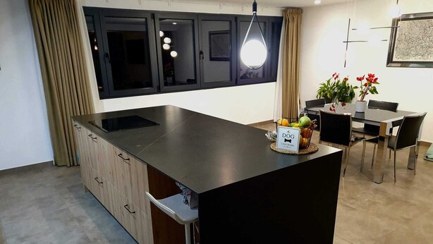 A modern kitchen with a central island, a dining area with a table and chairs, and a pendant light above the island.