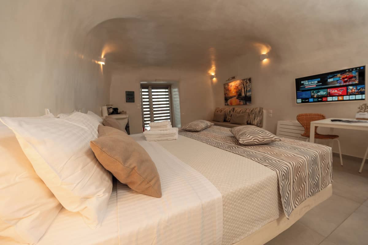 A bedroom with a large bed, a desk, and a television.