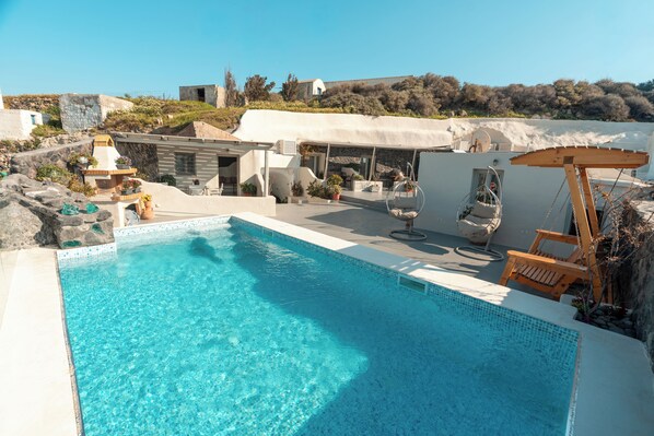 A clear blue pool with a sun lounger, a small outdoor kitchen, and a view of the surrounding landscape. - Rody Caves Oia (Oia)