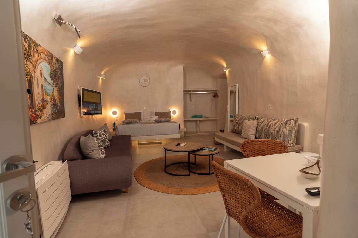 A cozy interior with a sofa, a dining table, and a small round table, all in a well-lit, arched room.