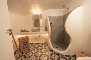 A bathroom with a bathtub, a shower, a toilet, a sink, and a mirror. - Rody Caves Oia (Oia)