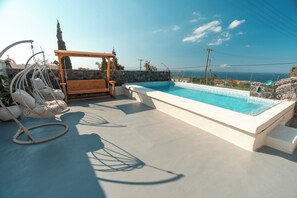 A rooftop pool with a pergola, hanging chairs, and a view of the ocean. - Rody Caves Oia (Oia)