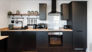 Une cuisine moderne avec des meubles de couleur noire, un four encastré, un four à micro-ondes et une machine à café.