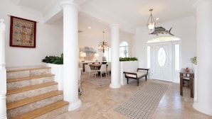 A spacious foyer with a grand staircase, a dining area, and a decorative ceiling.