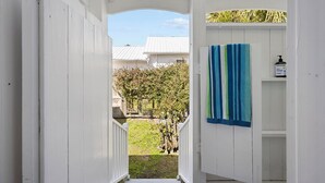 A white wooden corridor leading to a bathroom with a blue and green striped towel hanging on the wall.