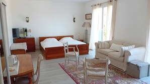 A hotel room with a bed, a sofa, a desk, a chair, a TV, and a lamp. - Bed and Breakfast 'Er Vingle - Chambre -  Suite' with Sea View, Shared Terrace and Wi-Fi (Locmariaquer)