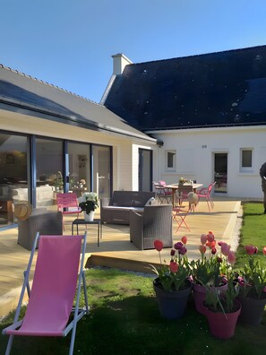 A modern house with a patio area featuring outdoor furniture, a lawn, and potted plants. - Bed and Breakfast 'Er Vingle - Chambre -  Suite' with Sea View, Shared Terrace and Wi-Fi (Locmariaquer)