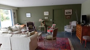 En stue med sofa, stole, sofabord, et tæppe, et fjernsyn og en dør.