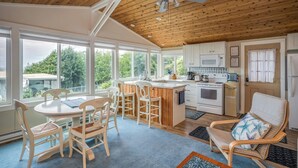A kitchen with wooden cabinets, a dining area with a table and chairs, and a ceiling fan. - Enchanted Cottage- Wood Fireplace & Cozy Vibes- Peaceful & Private-Ocean View (Arch Cape)