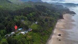 A coastal area with a beach, forested hills, and a few houses. - Enchanted Cottage- Wood Fireplace & Cozy Vibes- Peaceful & Private-Ocean View (Arch Cape)