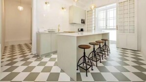 A modern kitchen with a central island, bar stools, pendant lighting, and a checkered floor. - Luxurious Architect-Designed 4-Bedroom Apartment in Madrid (Madrid)