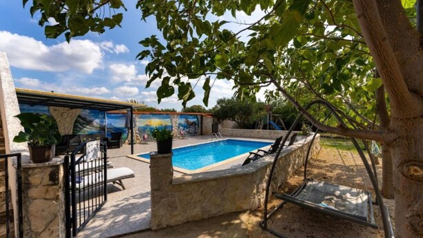 Una piscina con un muro in pietra, un murale e un albero.