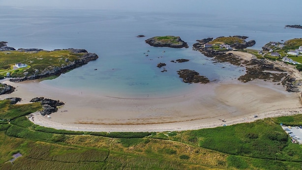 An aerial view of a coastal area with a sandy beach, rocky outcrops, and scattered houses. - Bodior Garden Cottage Bach (Holyhead)