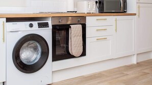 Una cocina moderna con armarios blancos, lavadora, horno y microondas.