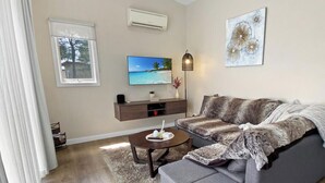 Ein modernes Wohnzimmer mit grauem Sofa, einem Couchtisch und einem flachbildfernseher an der Wand.
