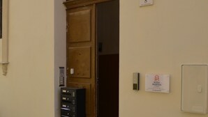 Entrada d'un edifici amb una porta de fusta, una closca de correu, un senyal encastat a la paret i un timbre.