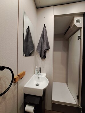 A modern bathroom with a white sink, a mirror, two towels, and a shower area. - Luxury houseboat including sauna with up to 8 berths in Berlin (Berlin)
