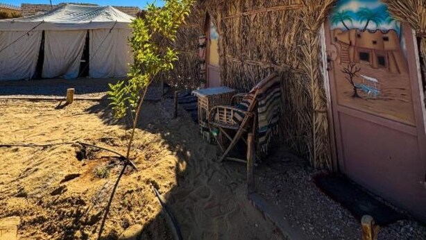 A desert campsite with thatched-roof huts, a tent, and a small table with a chair. - Double Room (Marsa Matrouh Governorate)