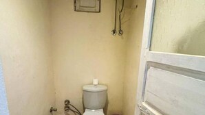 A small, narrow bathroom with a toilet, a white water heater mounted on the wall, and a wooden floor. - Double Room (Marsa Matrouh Governorate)