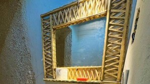 Un baño con un lavamanos blanco, un espejo con marco de madera y un perchero para toallas.