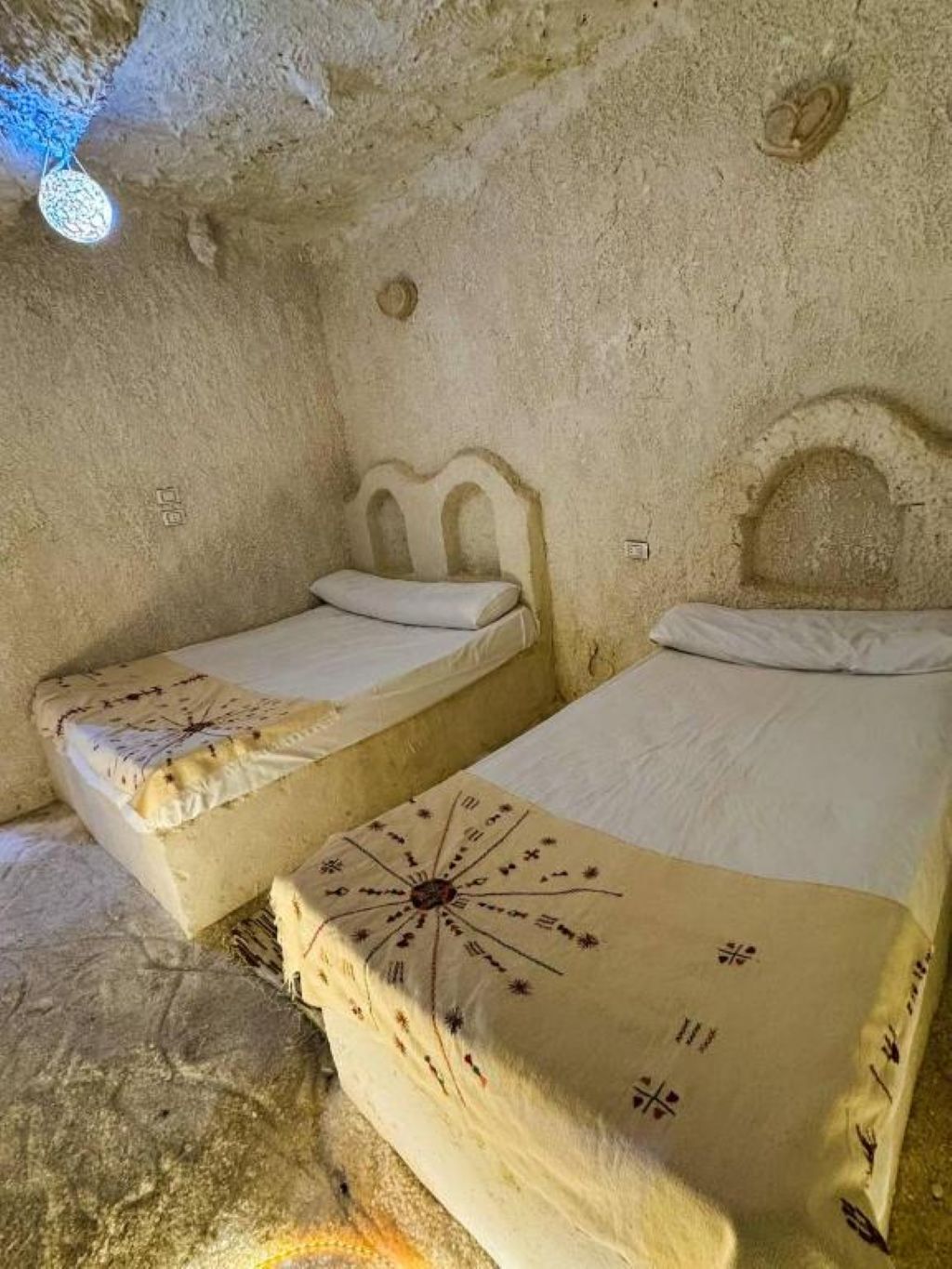 Une pièce qui ressemble à une grotte, avec deux lits, chacun recouvert d’une courtepointe à motifs originaux.