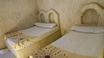 Une pièce qui ressemble à une grotte, avec deux lits, chacun recouvert d’une courtepointe à motifs originaux.