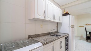 Eine Küche mit weißen Schränken, einer Arbeitsplatte aus Granit, einem Gasherd und einem Kühlschrank.