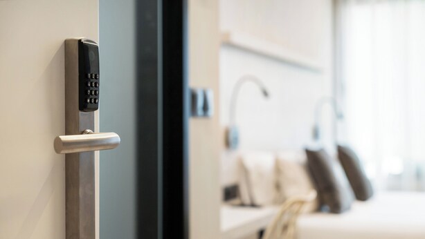 Une chambre d’hôtel moderne équipée d’un système d’accès par carte magnétique, d’un lit avec des oreillers et d’une table de chevet.