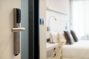 A modern hotel room with a keycard entry system, a bed with pillows, and a bedside table. - Dobo Madrid SB20 (Madrid)