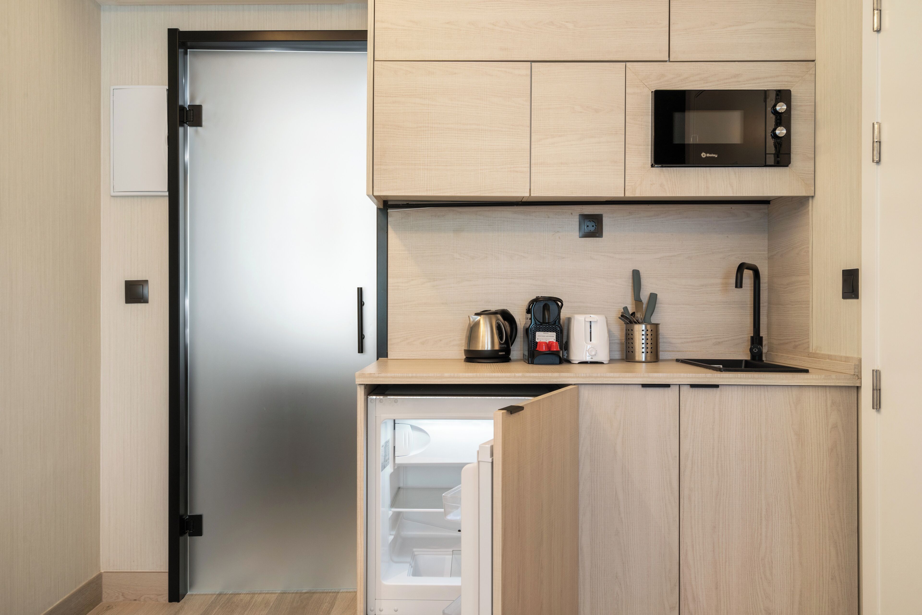 Cocina compacta con microondas, cafetera, tostadora y lavaplatos.