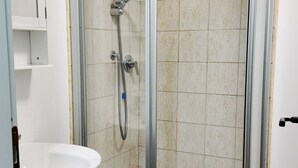 Ein Badezimmer mit Duschkabine aus Glas, einem weißen Waschbecken und gefliesten Wänden.