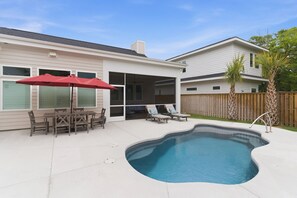 Un patio trasero con piscina, mobiliario de patio y una valla de madera.