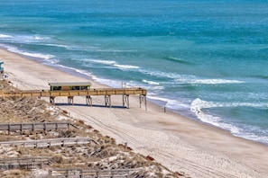 A beach with a wooden pier leading to a lifeguard station. - Private Pool, Carolina Beach Rental, Dog Friendly, Luxury Finishes, Sleeps 9 (Carolina Beach)