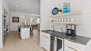 A modern kitchen with white cabinetry, a central island, and a coffee station. - Private Pool, Carolina Beach Rental, Dog Friendly, Luxury Finishes, Sleeps 9 (Carolina Beach)