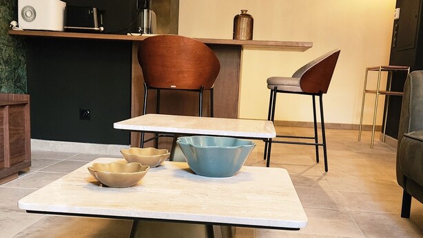 Une cuisine moderne dotée d’un îlot central, de deux chaises, d’une table et d’un plan de travail avec des appareils électroménagers.