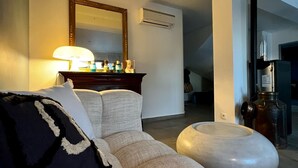 Una sala de estar moderna con un sofá, un reposapiés redondo, un espejo y una mesita con adornos.
