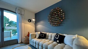 Una sala de estar moderna con un sofá, una mesa de centro redonda, una obra de arte decorativa y vistas al exterior.
