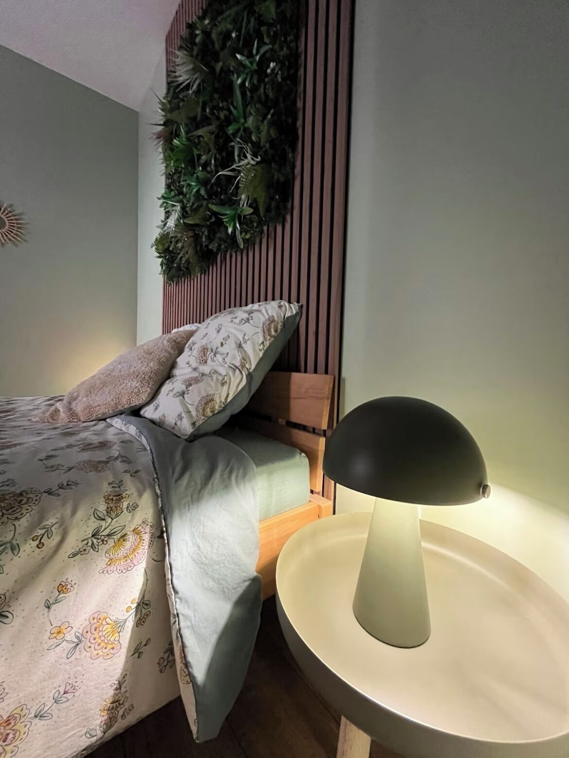Una camera da letto con un letto, una lampada da comodino, una pianta sospesa e una testiera in legno.