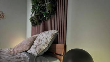 Una camera da letto con un letto, una lampada da comodino, una pianta sospesa e una testiera in legno.