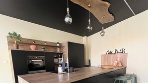 Een moderne keuken met een centraal kookeiland, barkrukken en hanglampen.
