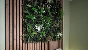 Een slaapkamer met een wand van houten latten, een bed met bloemenbedrukking en een kleine bedlamp.