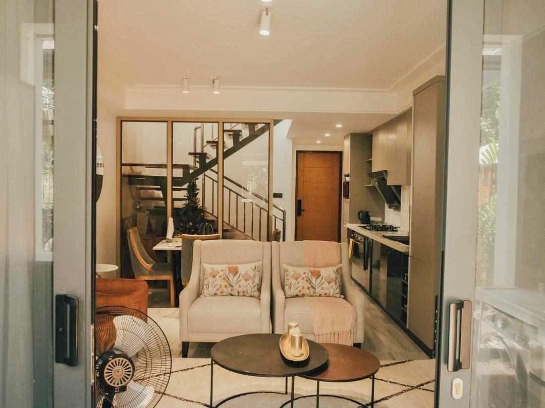 A modern living room with a sofa set, a coffee table, and a fan. A staircase leads to an upper floor.