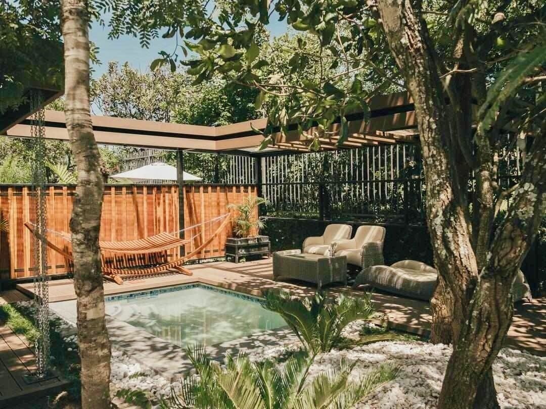A pool area with lounge chairs, a hammock, and a wooden fence.