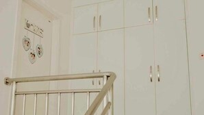 Un escalier avec une rampe métallique menant à une porte blanche ornée d’une inscription « LOVE » et de motifs en forme de cœur.