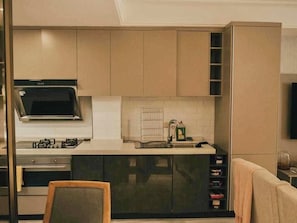 Een moderne keuken met een ingebouwde magnetron, gasfornuis en roestvrijstalen apparatuur.